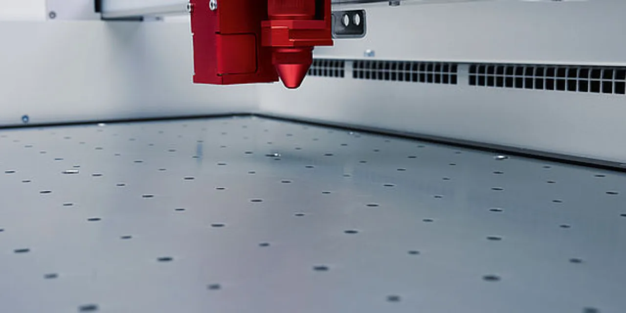 Close-up of Trotec Speedy series CO₂ laser cutter head above perforated aluminum worktable