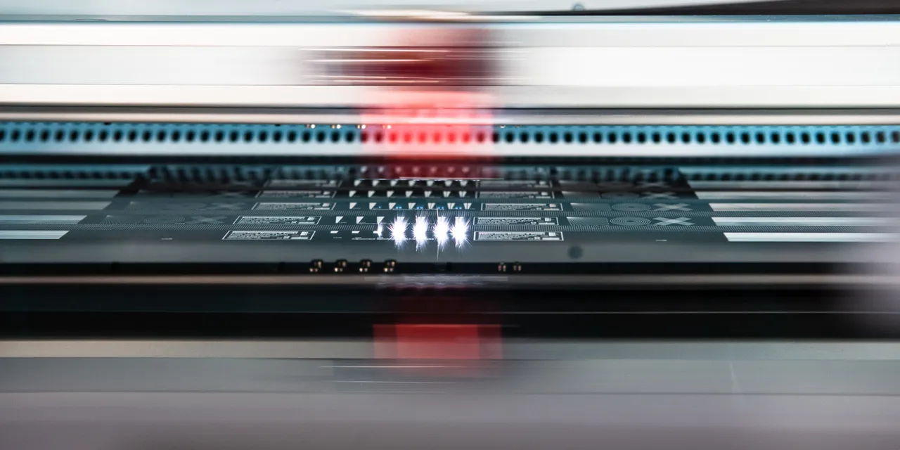 Trotec laser cutter engraving detailed circuit pattern on black sheet with high-speed precision