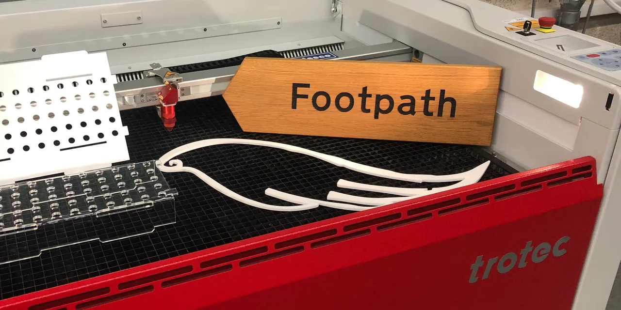 Trotec Speedy 400 CO₂ laser cutter processing wood, acrylic, and metal parts with precise results