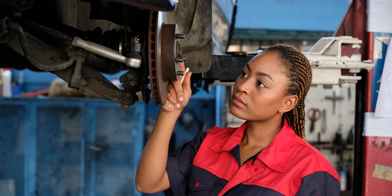 Female mechanic inspecting car brake disc in auto repair workshop