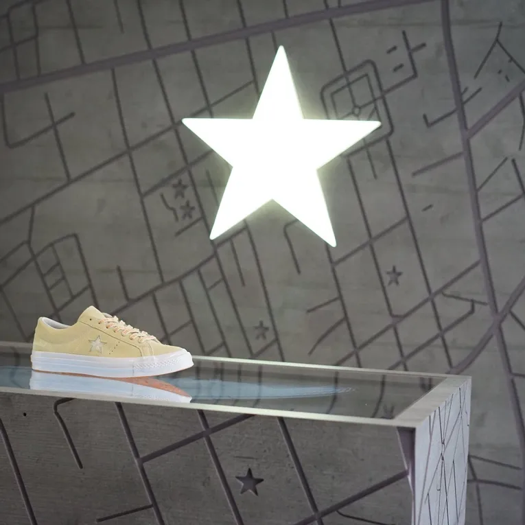 Laser-engraved map display with illuminated star and beige sneaker on Trotec-cut surface