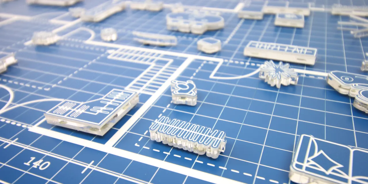 Laser-cut acrylic pieces on blueprint-style layout made with Trotec CO₂ laser cutter