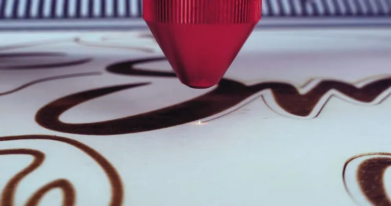 Trotec CO₂ laser cutter engraving detailed script text on wood surface