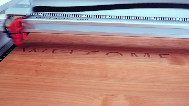 Trotec laser cutter engraving the word WELCOME on a wooden surface