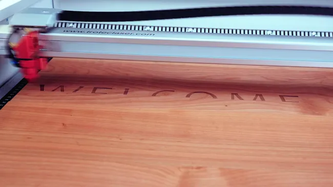 Trotec laser cutter engraving the word WELCOME on a wooden surface