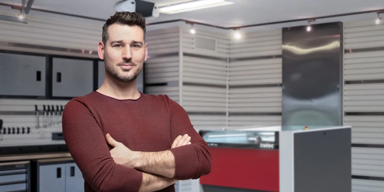 Man standing confidently beside Trotec Speedy series CO₂ laser engraver in modern workshop