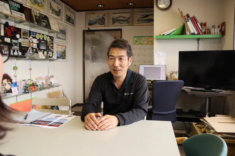 Man in office discussing Trotec laser engraving samples displayed on shelf