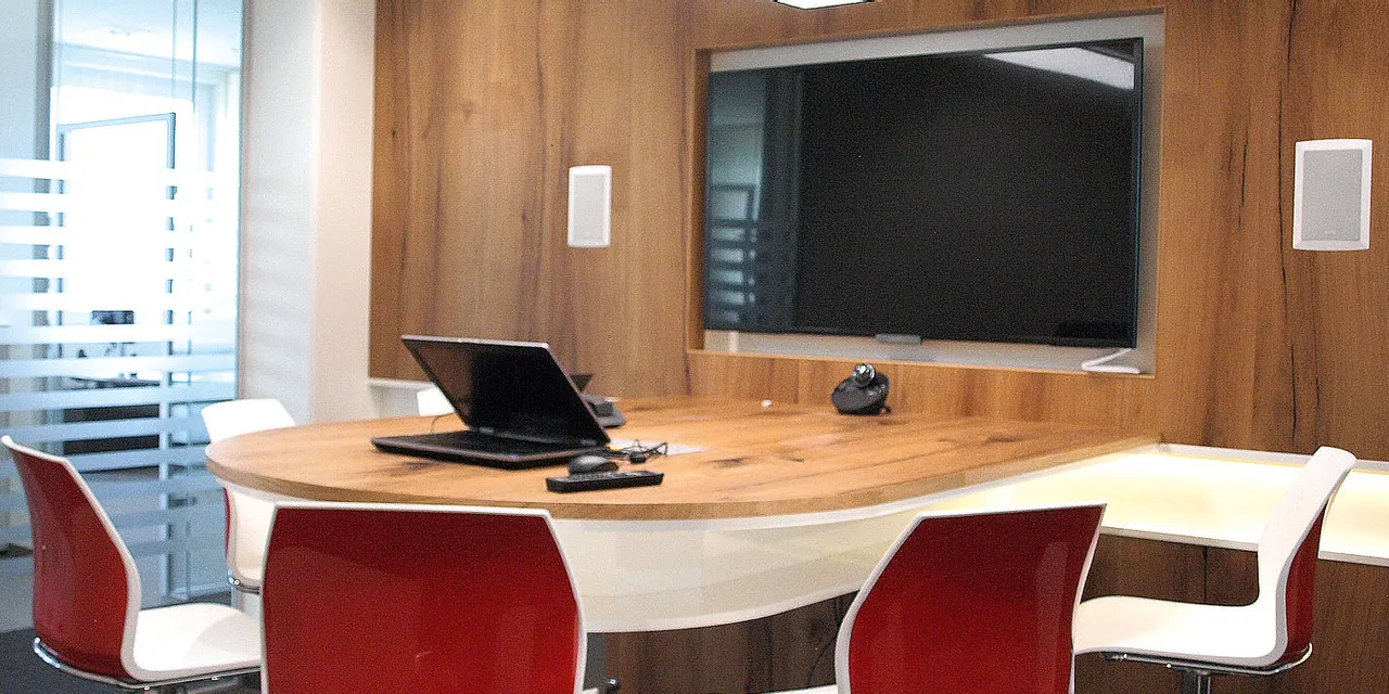 Modern Trotec meeting room with wood accents, glass walls, laptop, and large display screen