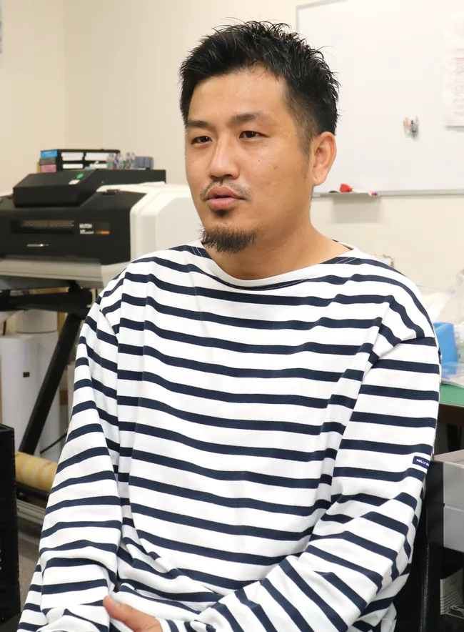 Man speaking in office with Trotec laser engraving equipment in background