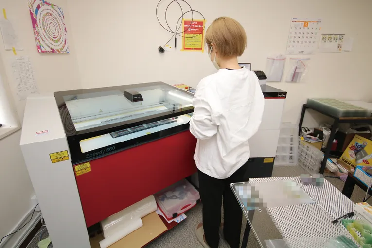 Operator using Trotec Speedy 360 CO₂ laser engraver in a workspace