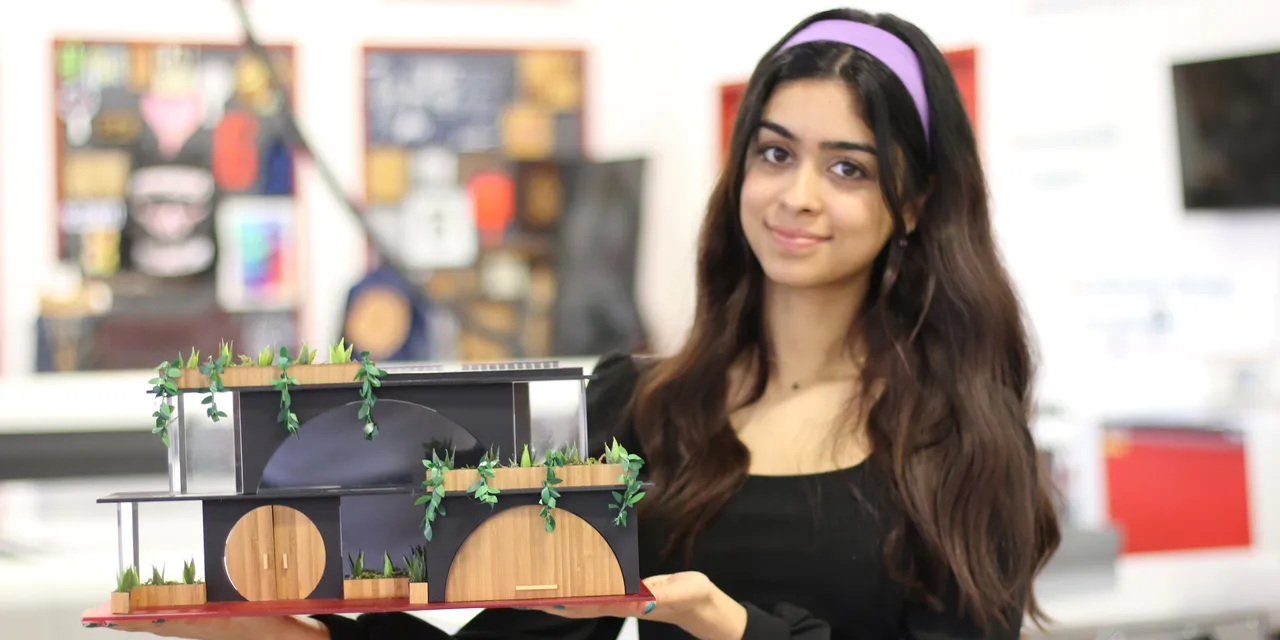 Student holds laser-cut architectural model made with Trotec CO₂ laser cutter in design lab
