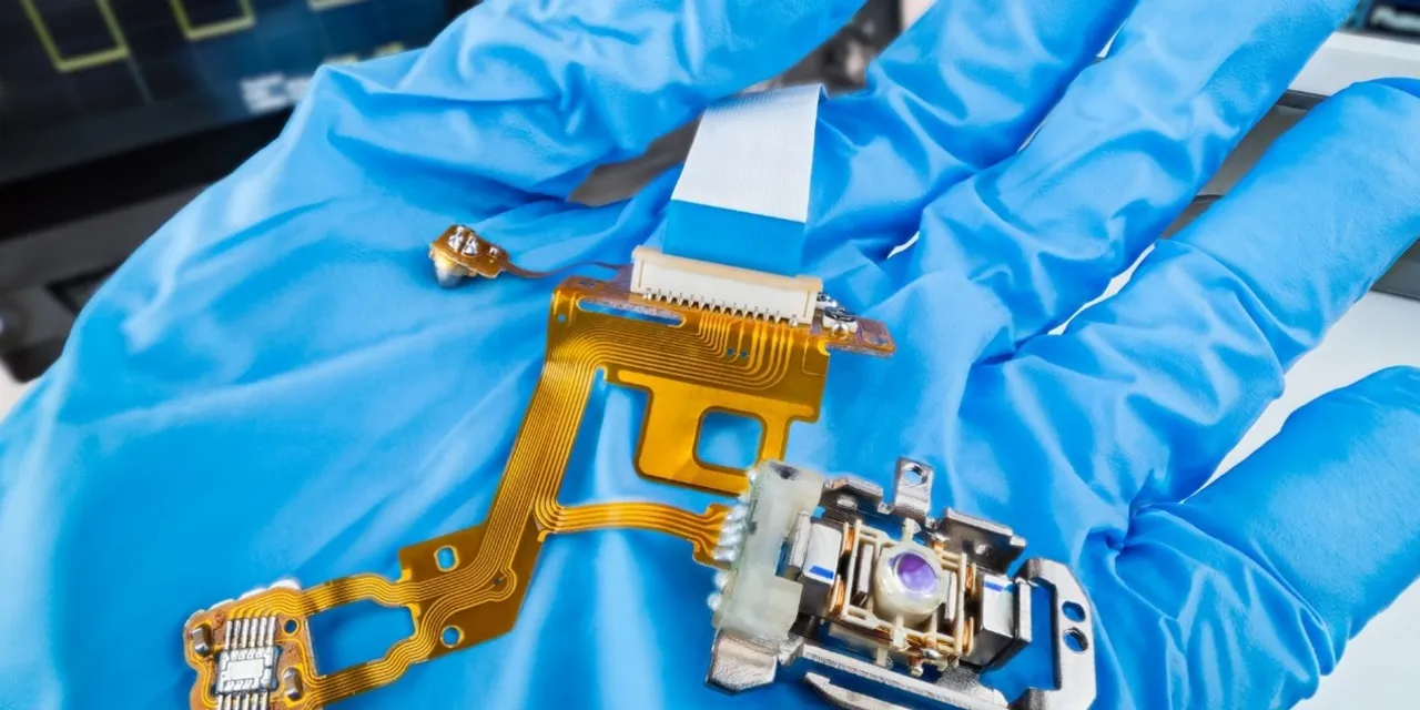 Technician holding precision laser-marked electronic circuit component with gloved hand