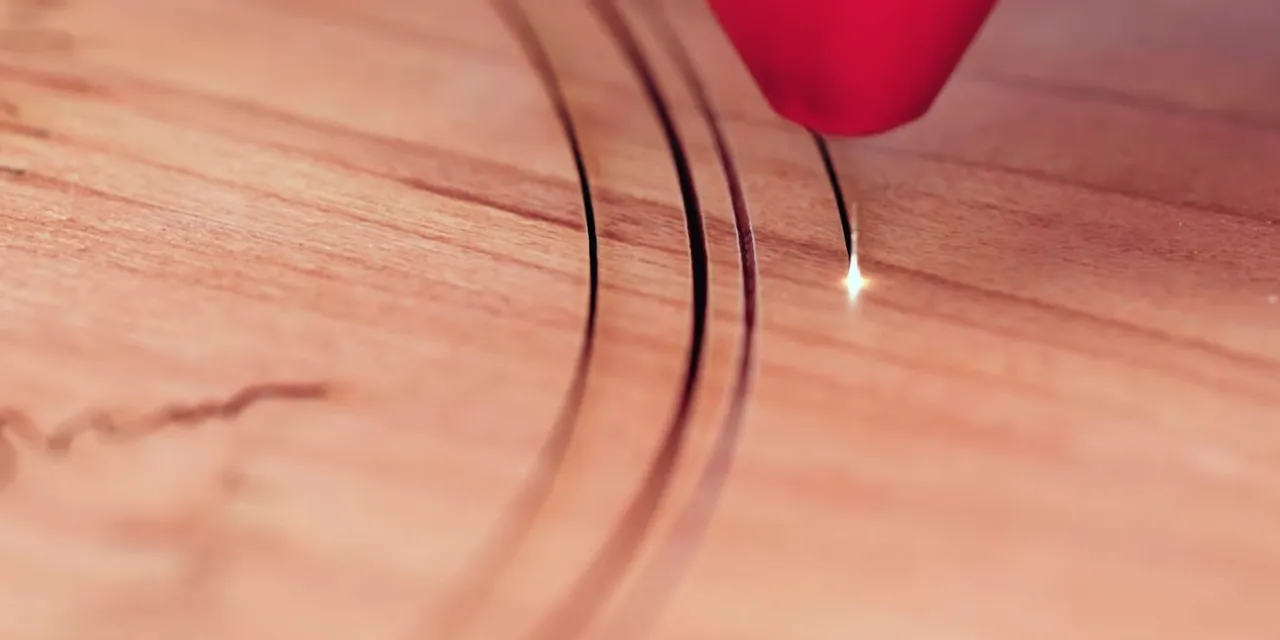 Trotec CO₂ laser cutter engraving curved lines on wooden surface with precision