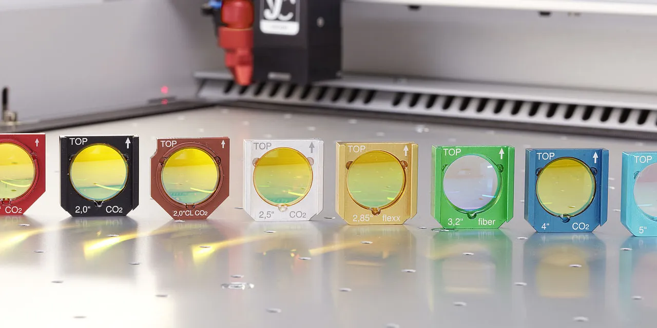 Trotec laser lenses for CO₂ and fiber laser cutters arranged by focal length on machine bed