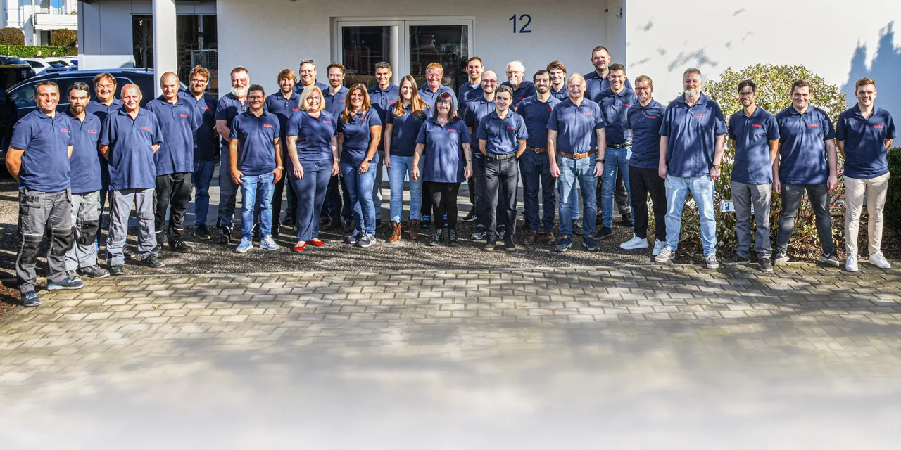 Trotec laser team group photo in front of building with TEAM motto sign
