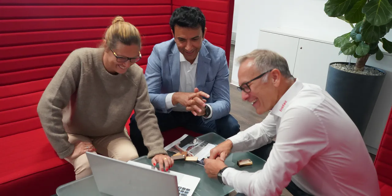 Trotec team discussing laser-engraved samples using Ruby software on a laptop