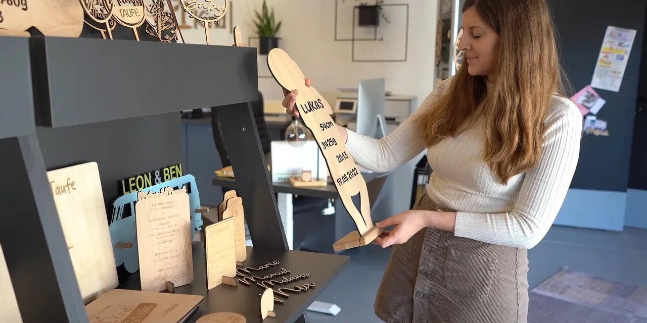 Woman displaying wooden signs created with Trotec CO₂ laser engraving machine