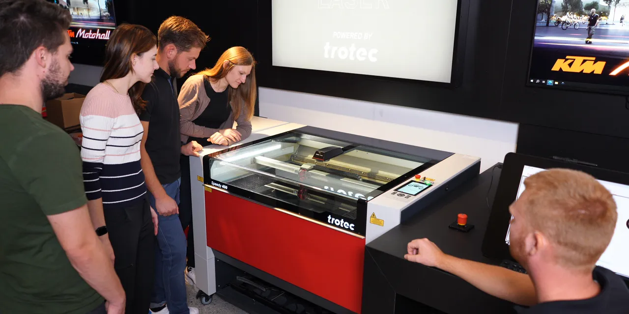 Group observing Trotec Speedy 400 CO₂ laser engraver during demonstration