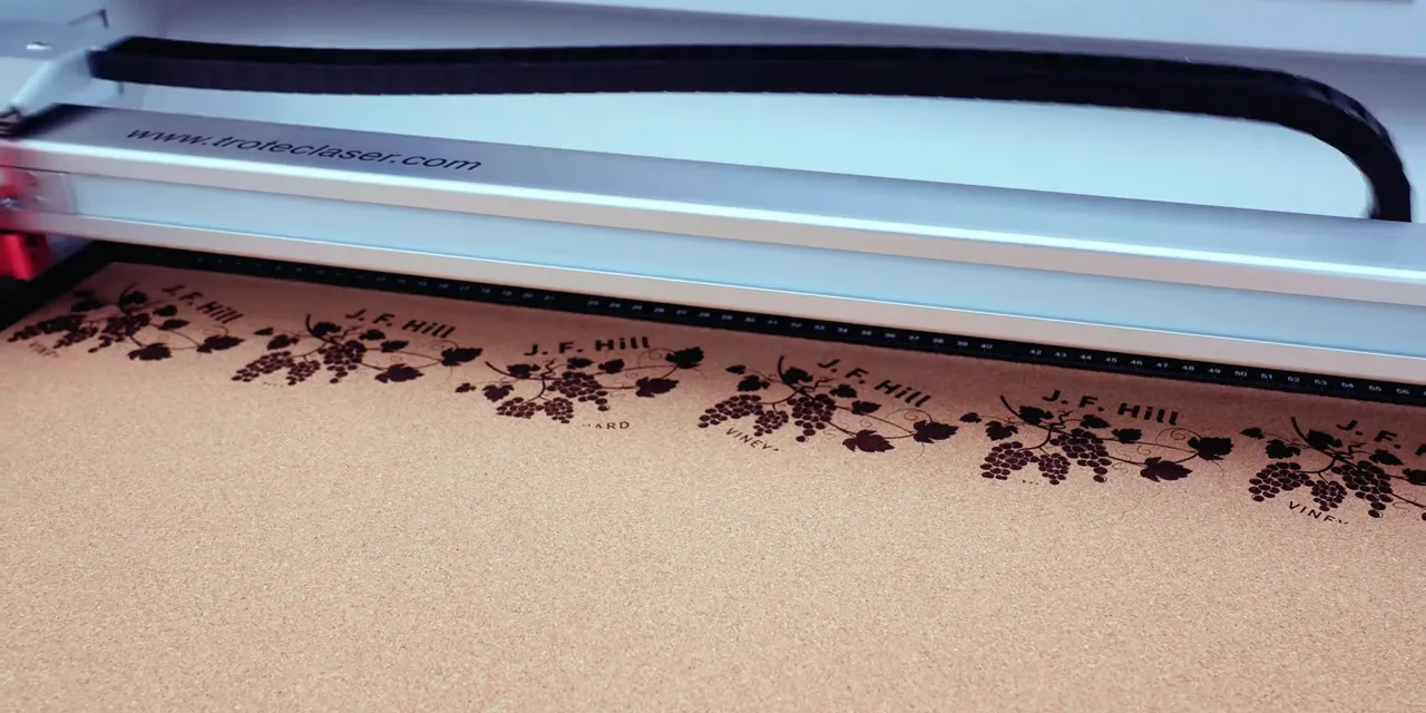 Trotec CO₂ laser engraver etching detailed grapevine design onto cork sheet